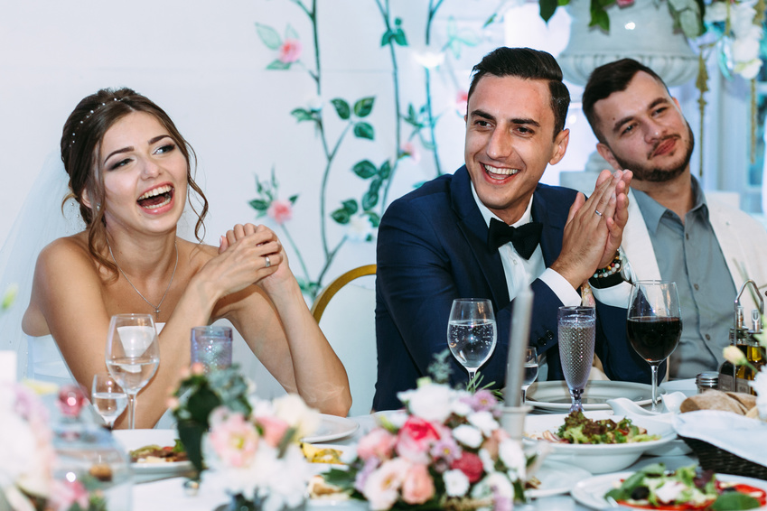 cheerful married couple at wedding reception dinner